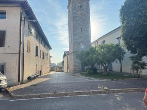 an empty street with a clock tower next to buildings at La maison Sophel in Pieris