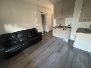 a living room with a black leather couch and a kitchen at La maison Sophel in Pieris