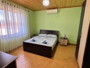 a bedroom with a bed in a room with green walls at Gezim guest house in Shirokë