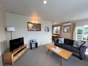 a living room with a couch and a tv at Waipoua Lodge in Aranga
