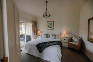 a bedroom with a bed and a chair and a window at Waipoua Lodge in Aranga
