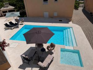 an overhead view of a pool with an umbrella and chairs at Ventana Pool Apartments - Stara Novalja in Stara Novalja