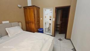 a bedroom with a bed and a bathroom with a toilet at Lita Residence in Yaoundé