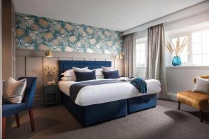 a bedroom with a blue bed and a blue chair at Budock Vean Hotel and Spa in Falmouth