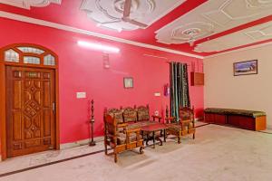 a living room with red walls and a wooden door at Hotel O Shiva Grand in Chinhat
