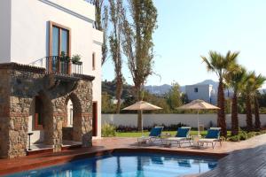 a villa with a swimming pool and two chairs and umbrellas at saraya otel in Bodrum City +17 photos
