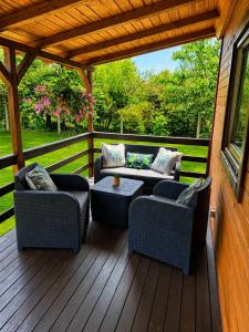 a patio with couches and a table on a wooden deck at Letniskowy Domek Paullo in Słajszewo