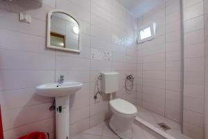 a white bathroom with a toilet and a sink at FIRST ROW Sea View in Šušanj +23 photos