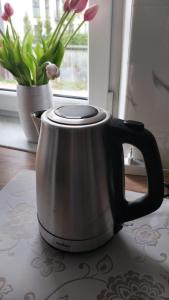 a tea kettle sitting on a table next to a vase of flowers at Blackapartment2Kawalerka in Olsztyn