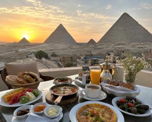 a table with food and drinks and the pyramids at Sun Hotel in Cairo