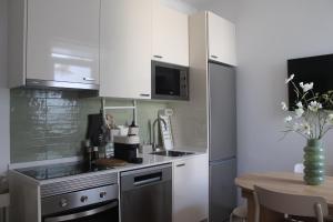 a kitchen with white cabinets and a table with a vase of flowers at La Petite Piété in Faro
