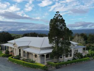 a white house with a tree in front of it at Waipoua Lodge in Aranga
