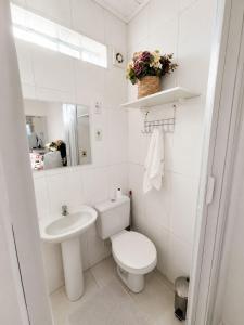 a white bathroom with a toilet and a sink at Casa próximo a Dutra- Excelente Localização in Lorena