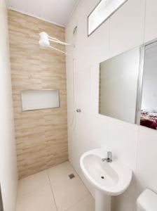 a white bathroom with a sink and a mirror at Casa próximo a Dutra- Excelente Localização in Lorena