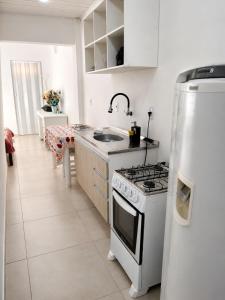 a white kitchen with a stove and a refrigerator at Casa próximo a Dutra- Excelente Localização in Lorena