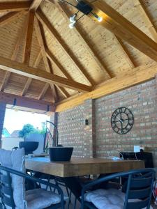 a large wooden table in a room with a clock on a brick wall at River House Batrovci in Batrovci +8 photos