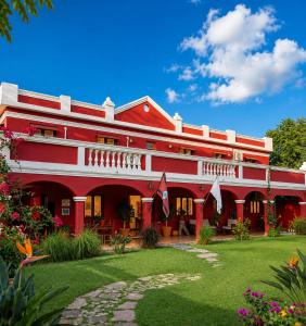 a red and white building with a green yard at El Crestón Hotel in Coronel Moldes