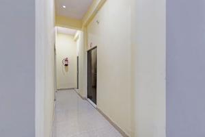 a hallway with white walls and a door at Hotel O City View in Alīgarh