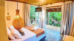 a bedroom with a bed and a large window at Aruana - café da manhã, piscina, na Reserva Sapiranga há 10 min da Vila de Praia do Forte in Castelo da Tôrre