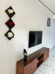Ein Wohnzimmer mit Fernseher und Blumen an der Wand in der Unterkunft Vip holiday inn in Aiyimensa