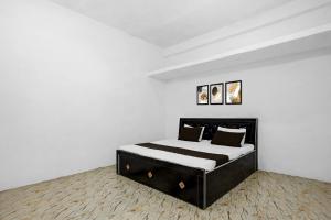 a white bedroom with a black bed with two pillows at SPOT ON Pk Hotel & Restaurant in Meja