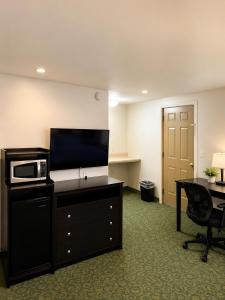 a hotel room with a tv and a desk and a microwave at DEEPWELL MOTEL in Owego