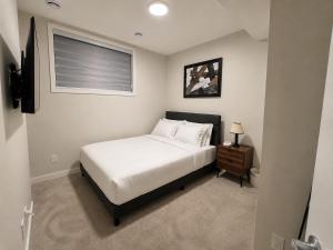 a bedroom with a white bed and a window at Cozy Private 1BR Basement Suite in Calgary