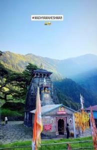 a small building with a tower on top of a mountain at Chaukhamba Pine Cottage & HomeStay in Rānsi