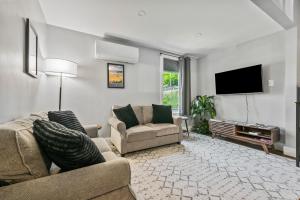 a living room with two couches and a flat screen tv at Willard Modern Cozy Apt 1st Floor in Whitefield