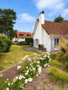 a white house with flowers in the yard at Maison chaleureuse proche plage et forêt in Neufchâtel-Hardelot