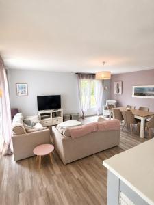 a living room with two couches and a tv at Maison chaleureuse proche plage et forêt in Neufchâtel-Hardelot