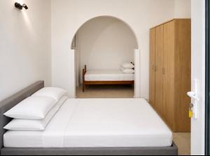 a white bedroom with a bed and an archway at Studios Annie in Bijela