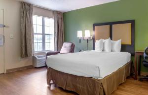 a hotel room with a large bed and a chair at Extended Stay America Select Suites - Raleigh - RDU Airport in Morrisville