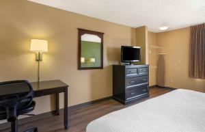 a hotel room with a bed and a desk with a television at Extended Stay America Select Suites - Raleigh - RDU Airport in Morrisville