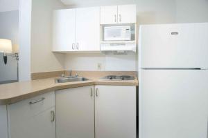 a kitchen with white cabinets and a white refrigerator at Extended Stay America Suites - Melbourne - Airport in Melbourne