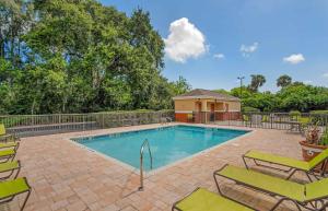 a swimming pool with chairs and a fence at Extended Stay America Suites - Melbourne - Airport in Melbourne