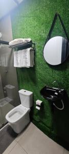 a green bathroom with a toilet and a sink at City suítes in Diamantino