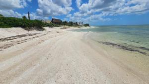 a sandy beach with a house and the ocean at Villas Aakal Petirojo in Chicxulub