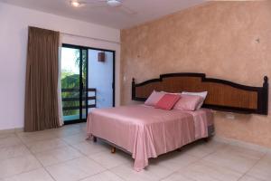 a bedroom with a bed with pink sheets and a window at Villas Aakal Petirojo in Chicxulub