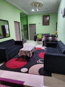 a living room with couches and a table on a rug at Quddus Inn villa in Wakaf Baharu
