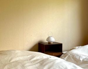 Eine Lampe auf einem Nachttisch neben einem Bett in der Unterkunft Room 48 in Takayama