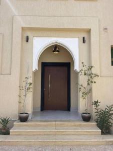 a front door of a building with two potted plants at 12 Durrat Al Arous - Rose Beach Villas in Durat Alarous