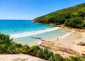 a group of people swimming in the ocean on a beach at Ar do Mar in Florianópolis