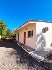 a small white house with a driveway at São Gabriel Centro Studios & Suítes in São Gabriel