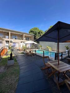 a patio with benches and an umbrella next to a pool at Los Lirios Apart & Suite in Puerto Iguazú