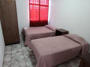 a room with two beds and a red window at DEPARTAMENTOS AMUEBLADOS CELIA in Morelia