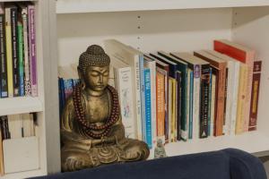 a statue sitting on a shelf with books at Nyima Tashi Buddhist Centre in Auckland