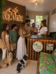 Eine Gruppe von Menschen steht mit zwei Hunden um eine Bar herum. in der Unterkunft Pousada Del Mare in Tutóia
