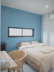 two beds in a room with a blue wall at บ้านรวมสุข the Happiness in Chiang Kham