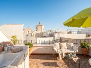 a balcony with a couch and an umbrella at Dimora BoxFish - Panorama terrace in Polignano a Mare